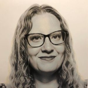 Nicole Smith is wearing glasses, smiling, and looking at the camera in this headshot.